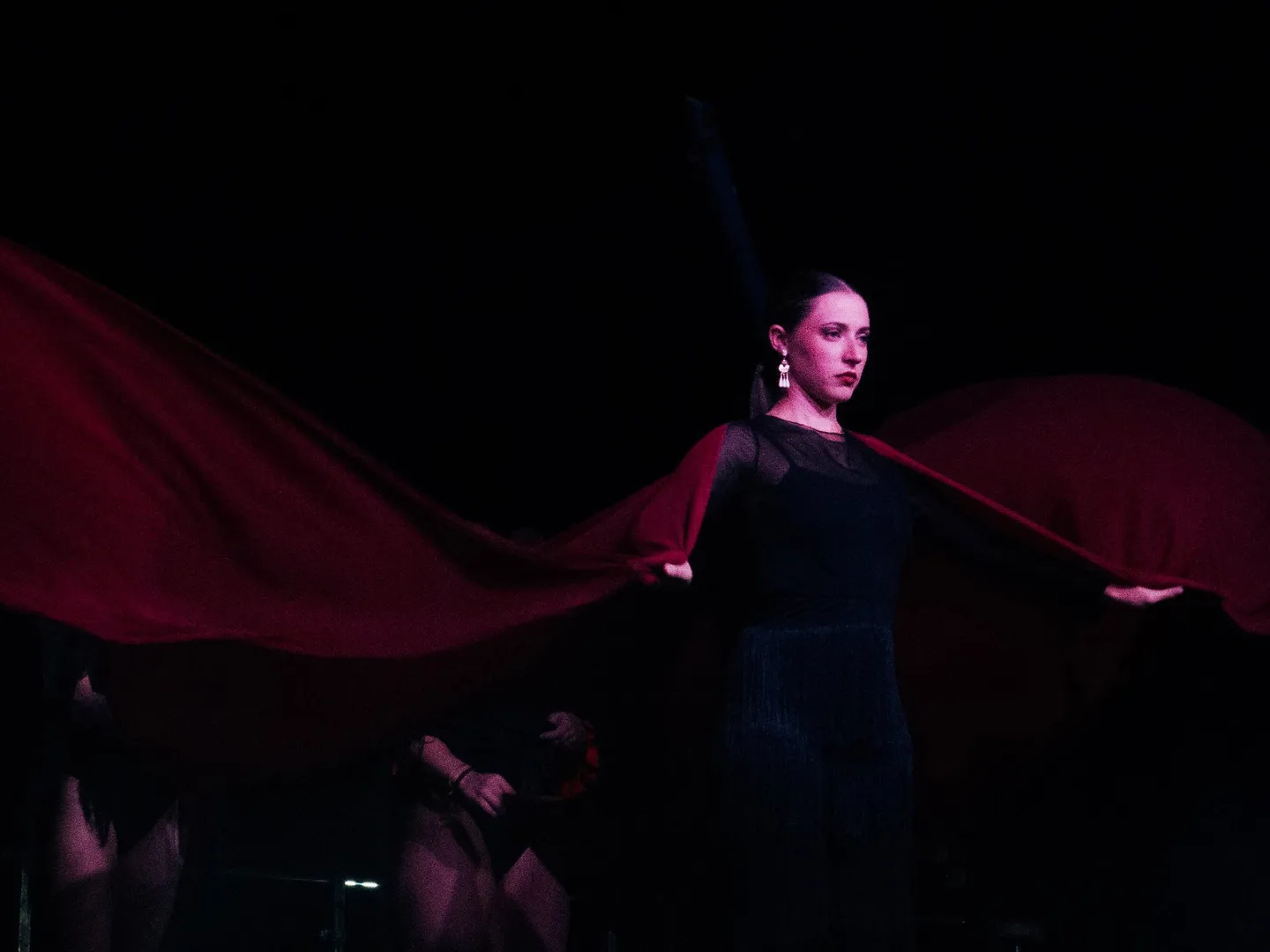 Menkub flamenco dancer on a dark stage holding a large red fabric